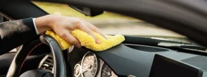 A used car owner wipes down the dashboard of his car.