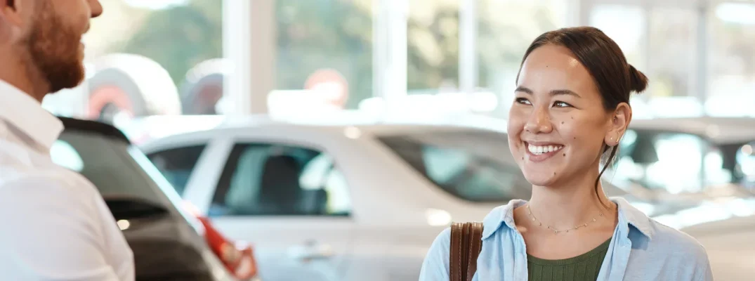 A woman talks to a dealership salesman about buying a used vehicle.